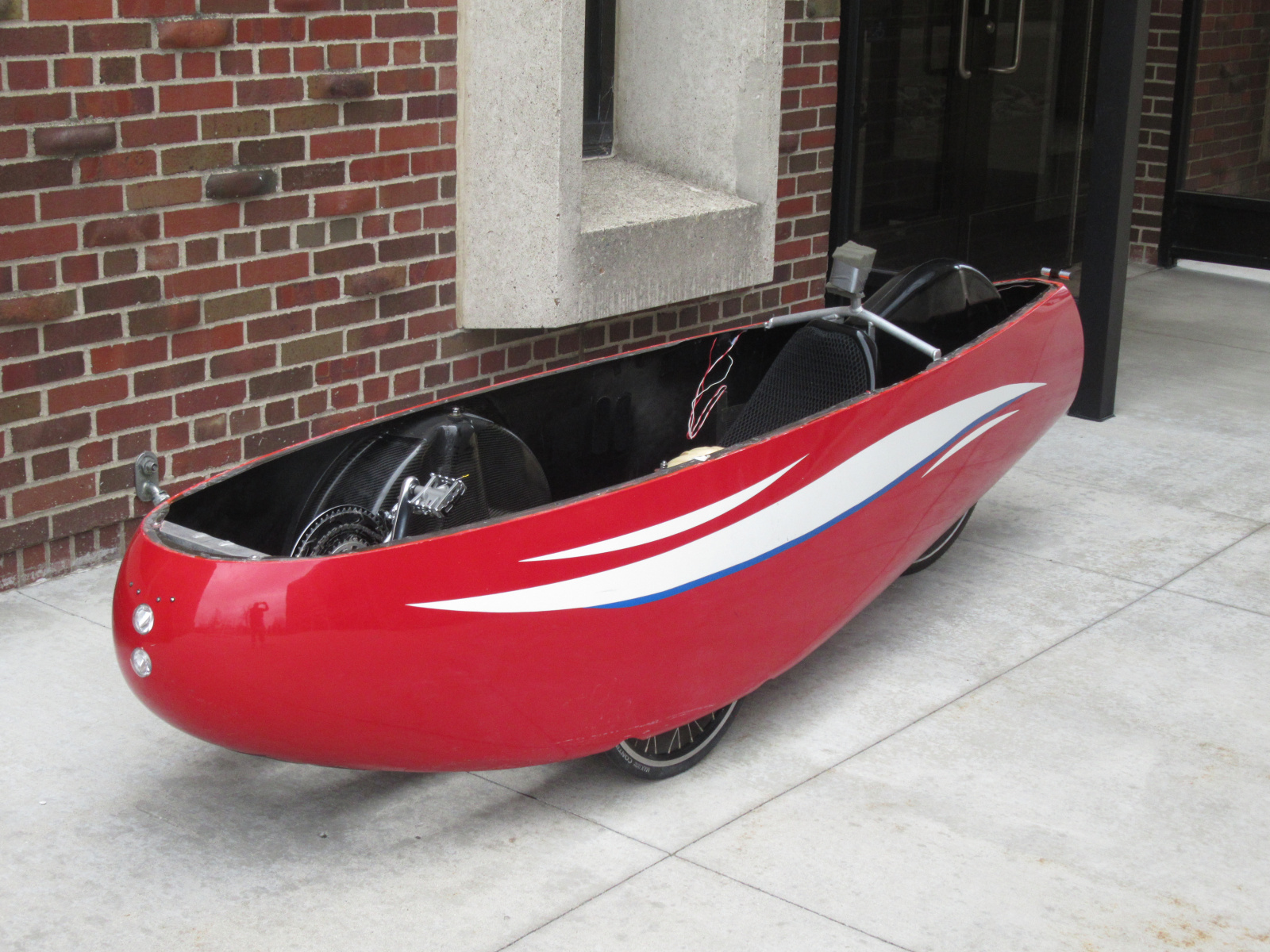 By March of 2024 I had the velomobile sufficiently cleaned up and fitted to me that I could take it out for some pedal-power only tests around campus. The top part of the body has been removed for access to the various components.