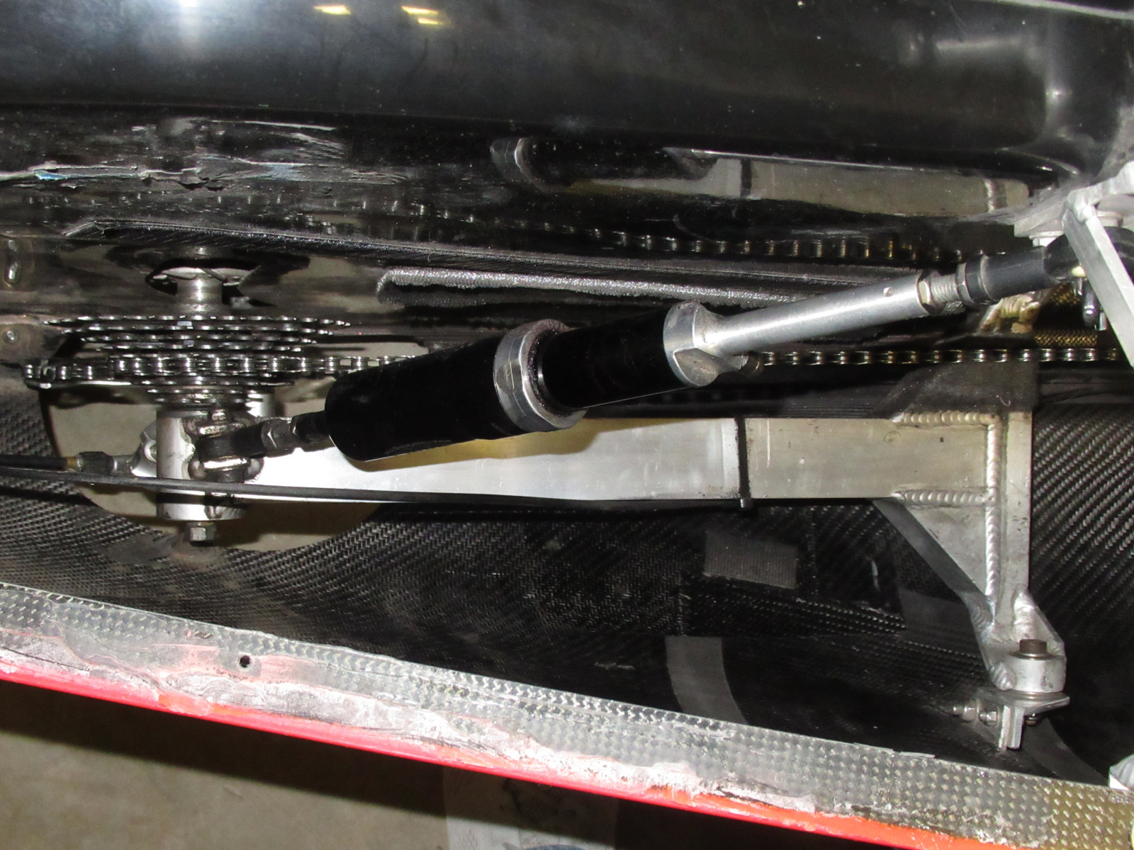 All three wheels have suspension, including the driven rear wheel. To facilitate inner tube changes in the field, all three wheels are also supported on only one side of the axle. Here one can see the aluminum swingarm supporting the drive side of the rear wheel, and the custom air shock. The wheel itself is not visible within the shroud at the top of this photo.